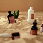 Cosmetic and skincare products artistically arranged on sand with cactus accents, evoking a desert vibe.